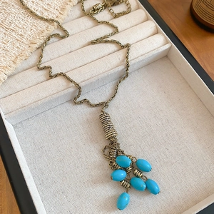 Detail of vintage bohemian necklace with turquoise tassels and gold metal wire on jewelry tray