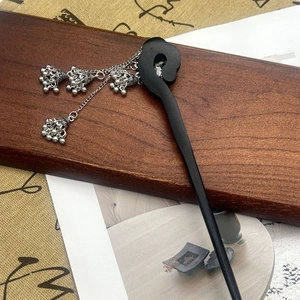 Detailed close-up of a vintage wooden hairpin with silver lotus tassel and small bells