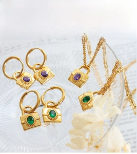 Detailed close-up of gold chain necklaces and earrings with purple and green stone padlocks