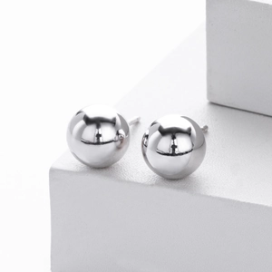 Macro shot of polished S925 sterling silver ball stud earrings on a white stone base