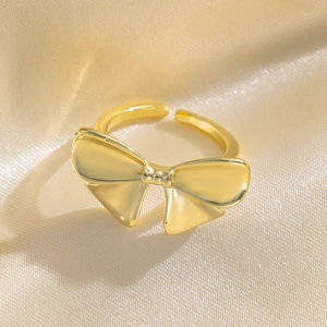 Elegant gold bow-shaped open ring displayed on champagne silk fabric background