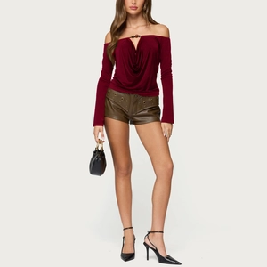 Full-body shot of a burgundy off-shoulder beaded top paired with brown leather shorts