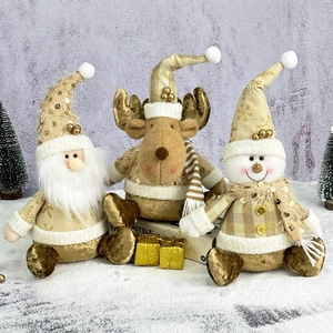 Three gold plush Christmas dolls with Santa, reindeer and snowman on snow base
