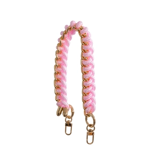 Detail of pink woven rope intertwined with golden metal chain and spring buckles