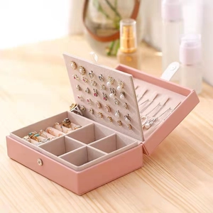 Pink portable jewelry organizer box for earrings and rings on a wooden desk