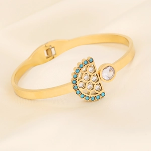 Macro detail of gold snake-style eye bracelet with blue beads and white zircon on silk