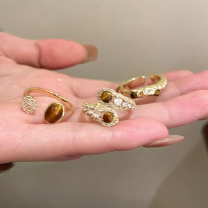 Detail of 18K gold plated tiger eye and zircon rings shown on a hand in natural light