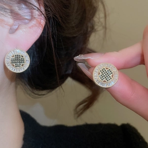 Close-up of gold plated round stud earring with black and clear cubic zirconia stones