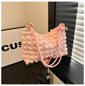 Detail of pink bubble texture fabric on a shoulder bag with gold hardware and leather strap