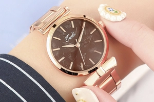 Detail of rose gold bow watch with coffee leaf pattern dial and metal strap