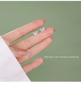 Macro detail of hand holding butterfly-shaped S925 sterling silver stud earrings