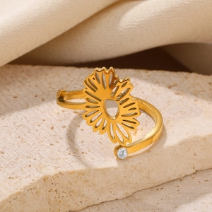 Detail of a gold sunflower ring with a white zircon accent on a marble surface