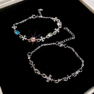 Detail of silver cross bracelets with colorful gemstones on black velvet background