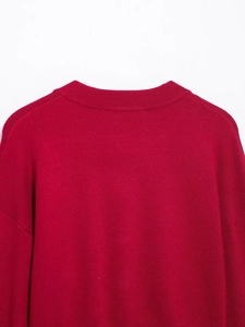 Close-up of the ribbed crew neck and fine knit texture on a red cardigan sweater