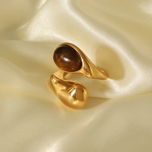 Détail d'une bague goutte dorée avec pierre œil de tigre sur tissu en soie