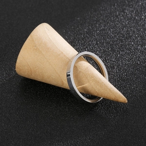 Close-up of polished silver stainless steel ring displayed on a wooden cone stand