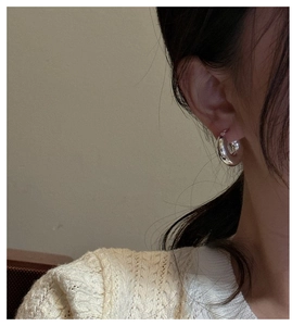 Gros plan d'une boucle d'oreille créole épaisse en argent S925 portée par un mannequin