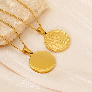Detail of gold stainless steel zodiac coin necklaces on beige silk and natural stone