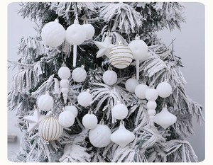 Weiße Weihnachtsbaumschmuck-Set mit Sternen und Kugeln auf schneebedecktem Baum