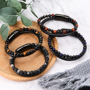 Men's woven leather bracelet with volcanic stone and tiger eye beads on marble surface