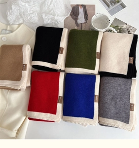 Close-up of knit scarves in multiple colors with contrast borders and leather tags