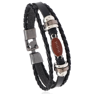 Close-up of multilayer braided leather bracelet with vintage brown rugby metal charm