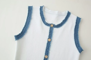 Détail de gilet en tricot blanc avec bordure en jean bleu et boutons dorés