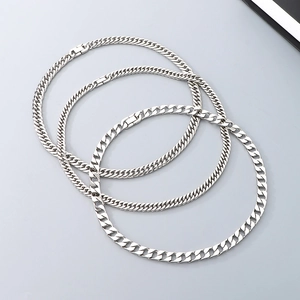 Close-up of three polished silver stainless steel Cuban link chains in an intertwined layout