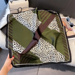 Detail of leopard print silk scarf with green and brown geometric pattern on plush rug