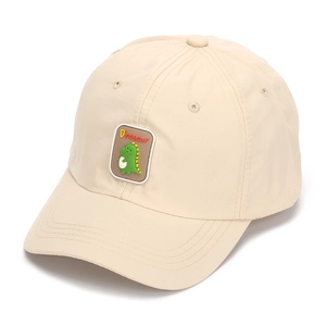 Detailed close-up of beige kids baseball cap featuring a green dinosaur patch and text
