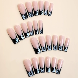 Detail of long coffin press-on nails with black tips and white Halloween ghost patterns