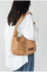 Macro detail of brown corduroy hobo bag showing the side pocket and leather logo tag