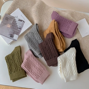 Vue à plat de chaussettes en maille torsadée colorées aux textures variées et tons d'automne