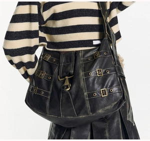 Detail of vintage black hobo bag with bronze buckles and punk style decorative straps
