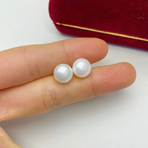 Close-up of two lustrous white round freshwater pearls held by hand over a velvet box