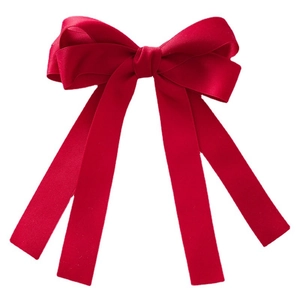Detail of a large red velvet ribbon hair bow with elegant flowing streamers