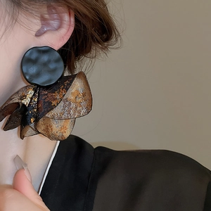Macro shot of vintage black matte discs and golden pleated fabric floral earrings
