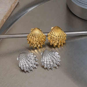 Macro detail of gold and silver seashell earrings with fine radial texture on metal