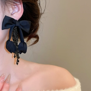 Close-up of elegant black fabric bow earrings with crystal tassel beads on model