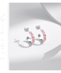 Detailed close-up of s925 silver hoop earrings with pink enamel hearts on white background