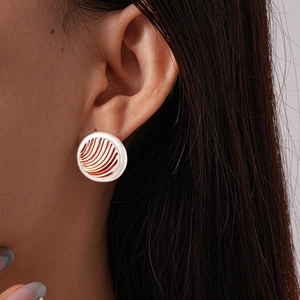 Close-up of geometric round gold and white enamel stud earring on model's ear