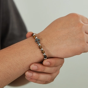 Close-up of a men's beaded tiger eye stone bracelet with a metallic anchor charm detail