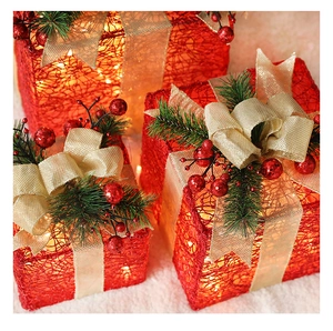 Detail of Christmas gift boxes with red mesh, gold ribbons, and warm LED lights