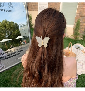 Close-up of matte white butterfly hair claw clip worn on hair in an outdoor setting