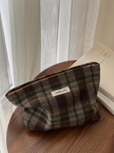 Close-up of retro plaid wool makeup bag with simple wish label on a wooden stool
