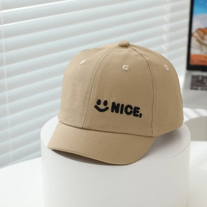 Close-up of khaki short-brim baseball cap featuring black smile face and NICE embroidery