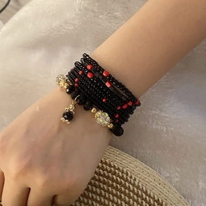 Detail of bohemian multilayer bracelet with red and black beads and crystal pendants