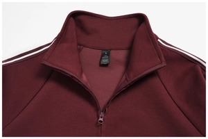 Detail of burgundy zip-up sweatshirt collar with wash label and white shoulder stripes