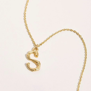 Collier doré en acier 316L avec pendentif lettre S arborant une texture de bambou