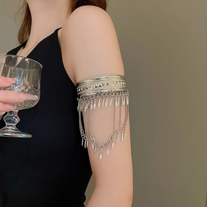 Gros plan du bracelet de bras boho argenté avec motifs géométriques et pampilles plumes